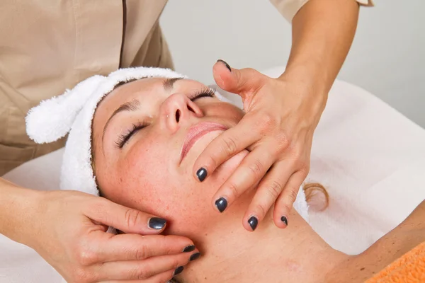 Beautiful young woman receiving facial massage with closed eyes — Stock Photo, Image
