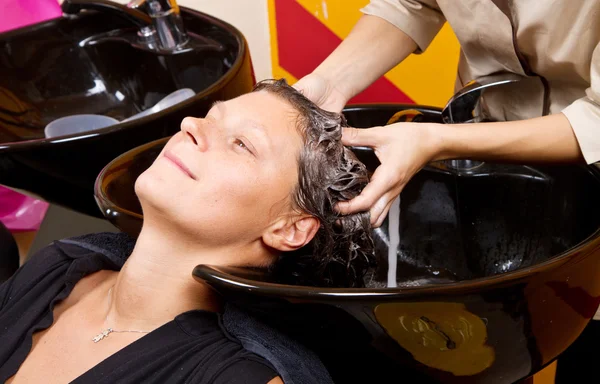 Hairdressers hand washing female customer's hair in salon — Stock Photo, Image