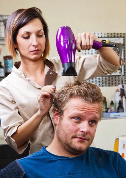 Hermoso hombre en la peluquería golpe secándose el pelo — Foto de Stock