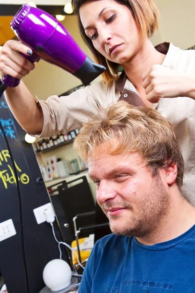 Beautiful man at the hairdresser blow drying his hair — Stock Photo, Image
