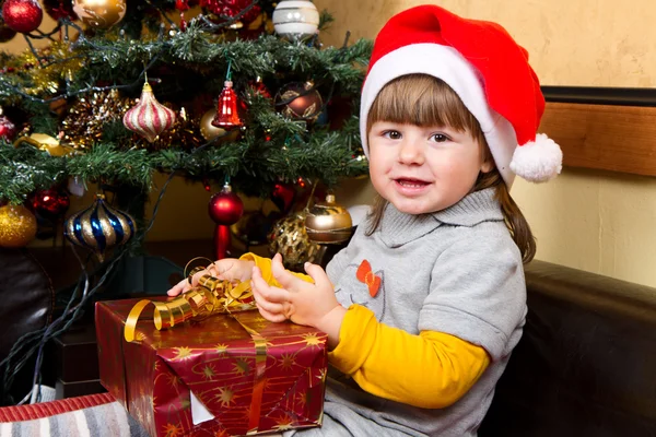 Gelukkig kind in Kerstman hoed openen van de doos van de gift van Kerstmis — Stockfoto