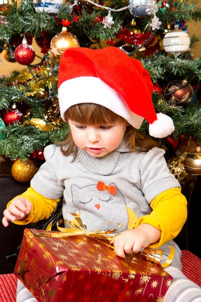 Gelukkig kind in Kerstman hoed openen van de doos van de gift van Kerstmis — Stockfoto