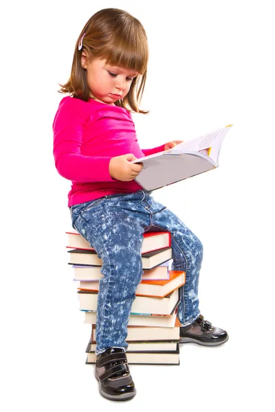 Meisje, zittend op stapel boeken — Stockfoto