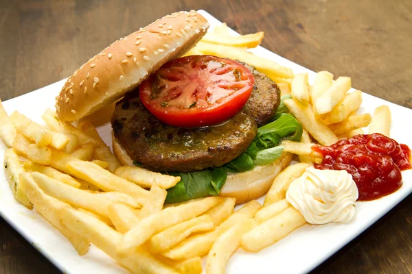 Hamburger with potatoes on wooden background — Stock Photo, Image