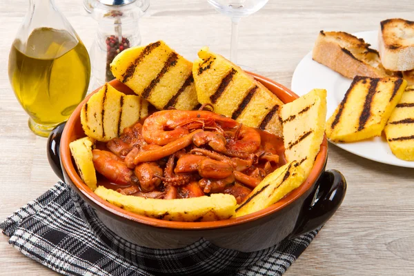 Fish soup with grilled polenta on crock pot — Stock Photo, Image