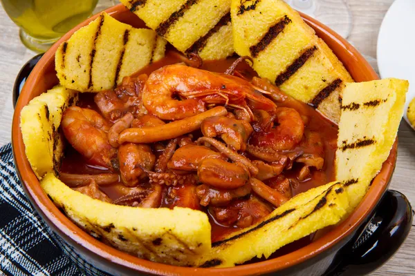 Fish soup with grilled polenta on crock pot — Stock Image Fish soup with grilled polenta on crock pot Royalty Free Stock Images
