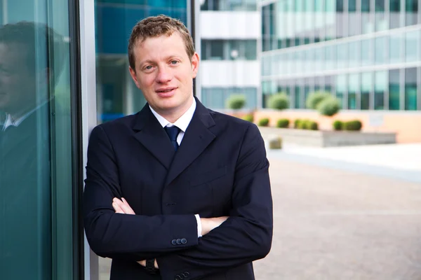 Smiling young businessman standing outside a building — Stock Photo, Image