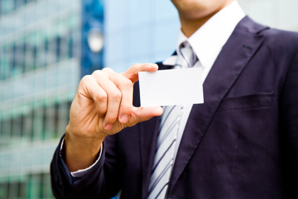 young businessman holding visit card in hand and standing in the