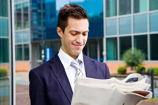 Smiling young businessman standing outside a building — Stock Photo, Image