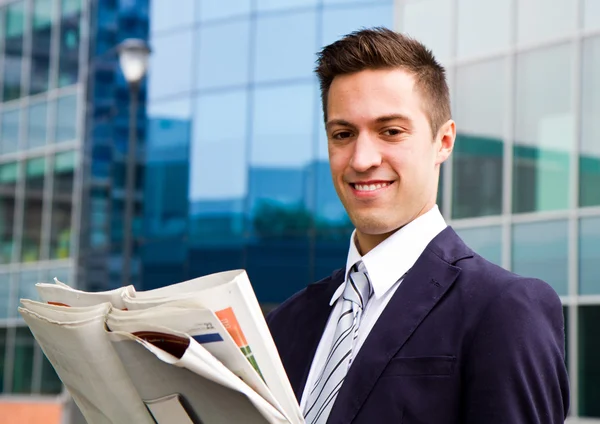 Usměvavý mladý podnikatel stojící mimo budovu — Stock fotografie