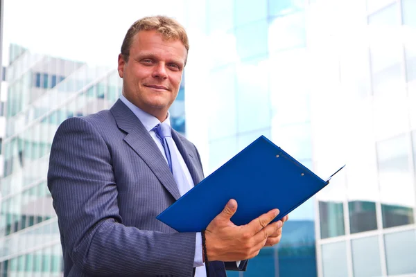 Portrait of happy smiling young businessman with blue folder — Stock Photo, Image