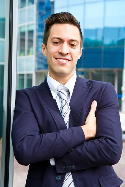 Smiling young businessman standing outside a building — Stock Photo, Image