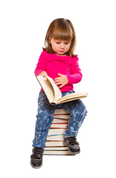 Kleines Mädchen sitzt auf Bücherstapel — Stockfoto