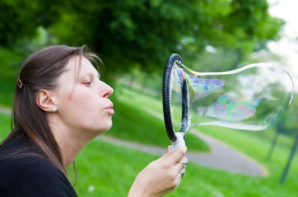 Mujer inflando burbujas de jabón de colores en el parque de primavera — Foto de Stock