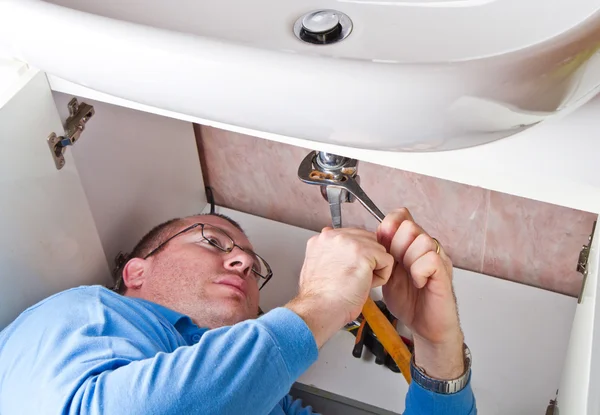 Un fontanero reparando un lavabo roto en el baño —  Fotos de Stock