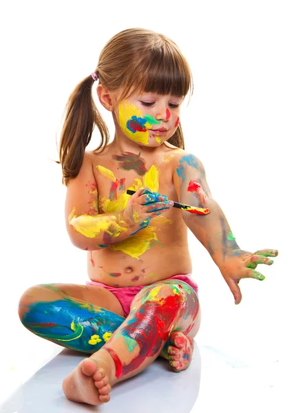 Pieni tyttö maalaus siveltimellä ja värikkäillä maaleilla — kuvapankkivalokuva