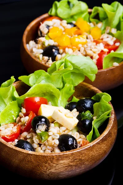 Wood bowl with spelt salad with olives and tomatoes — Stock Photo, Image