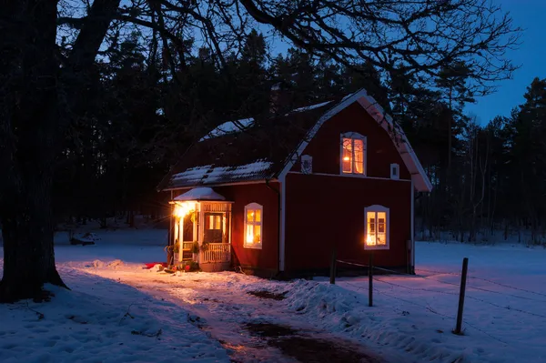 Red painted Swedish wooden house in a wintry landscape at night