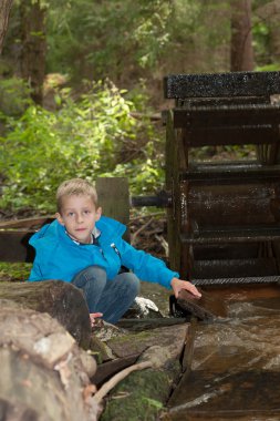 Young boy with an old water wheel clipart