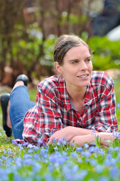 Hermosa joven acostada en un prado con Scilla bifolia en s —  Fotos de Stock