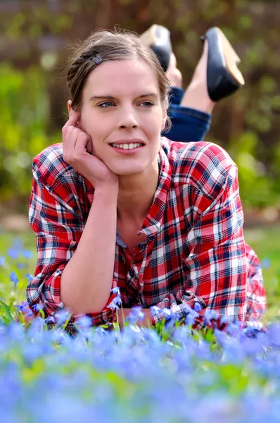 Vacker ung kvinna liggande på en äng med scilla bifolia i s — Stockfoto