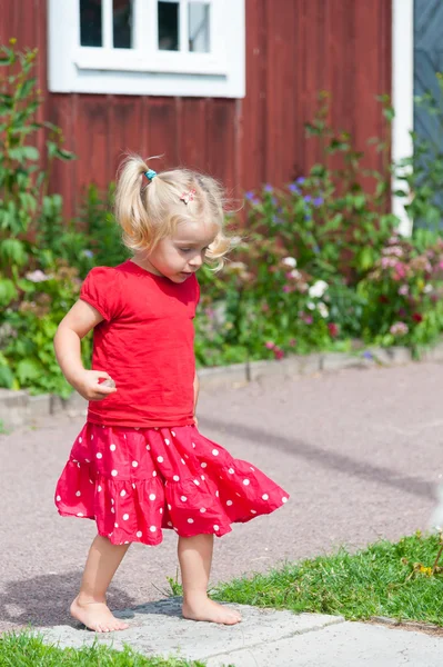 Στο κόκκινο καλοκαιρινό φόρεμα το χαριτωμένο κοριτσάκι Royalty Free Εικόνες Αρχείου