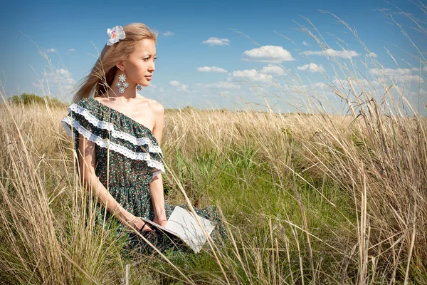 Азиатка с книгой, сидящей на траве — стоковое фото