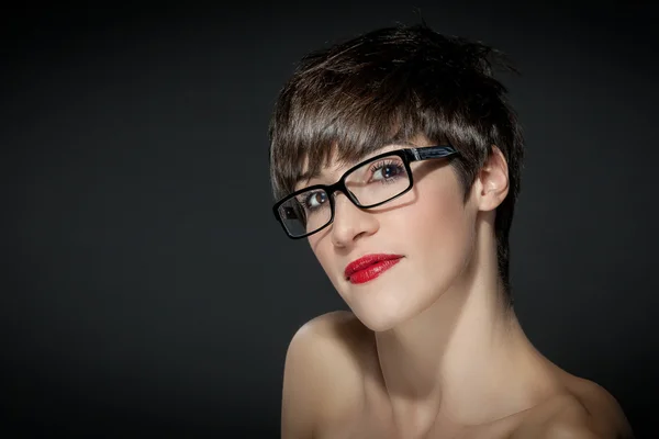 Mladá žena s brýle před šedé pozadí — Stock fotografie