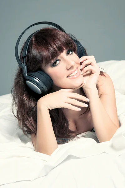 Mujer sonriente en lencería y auriculares en la cama —  Fotos de Stock