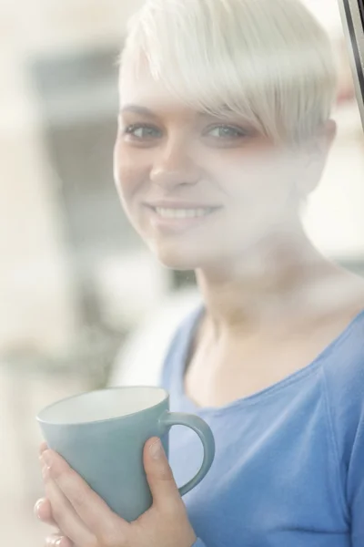 Atractiva mujer disfrutando de su café detrás de una ventana —  Fotos de Stock