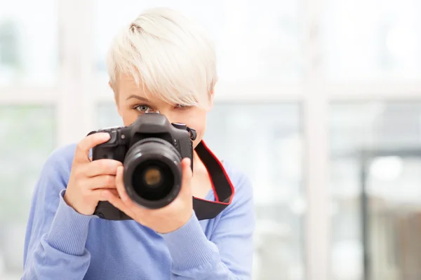 Kvinnlig fotograf med dslr hemma sitter på golvet — Stockfoto