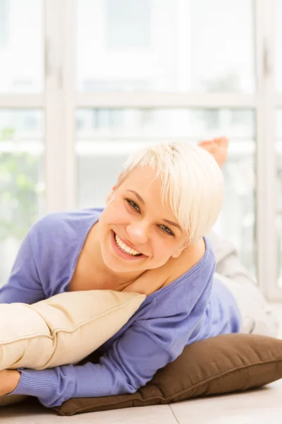 Femme souriante aux cheveux courts posée sur un oreiller — Photo