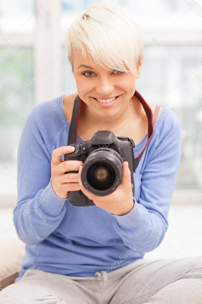 Female photographer with DSLR at home sitting on the floor
