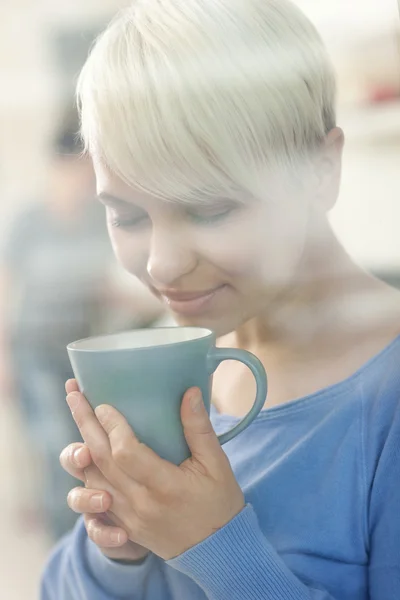 Vonzó nő élvezi a kávéját, egy ablak mögött — Stock Fotó