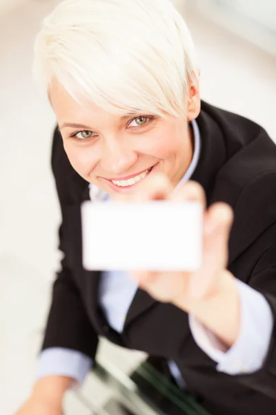 Businesswoman holding business card while smiling towards the ca — Stock Photo, Image