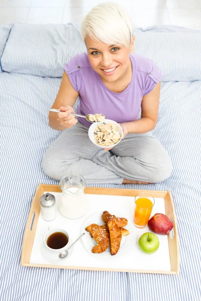 年轻的金发女人在卧室里吃早餐 — 图库照片