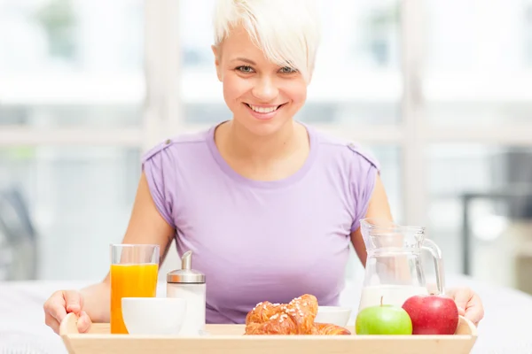 Mujer rubia joven está desayunando en el dormitorio — Foto de Stock