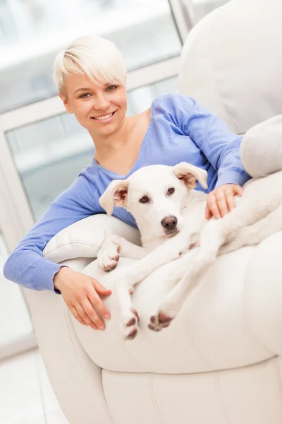 Mujer sentada con un perro joven en el sofá —  Fotos de Stock