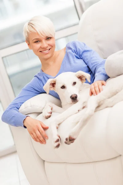 Mujer sentada con un perro joven en el sofá — Foto de Stock