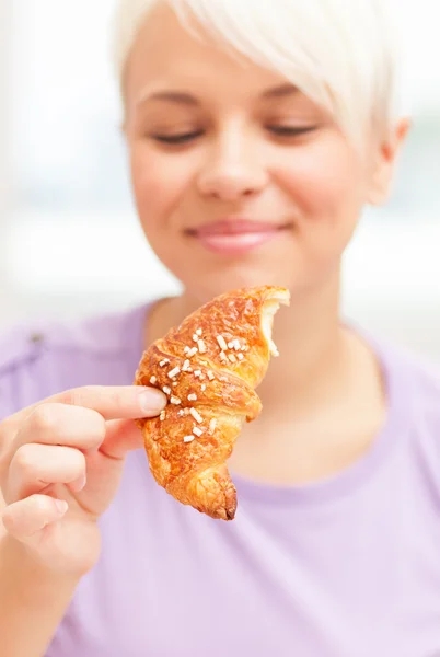 Frau schaut hungrig auf ein Croissant — Stockfoto