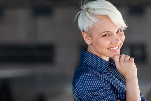 Femme d'affaires portant une chemise et souriant devant un dos sombre — Photo