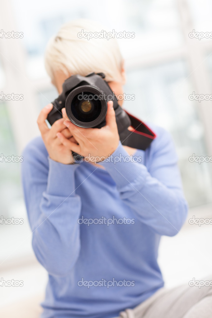 Female photographer with DSLR at home sitting on the floor