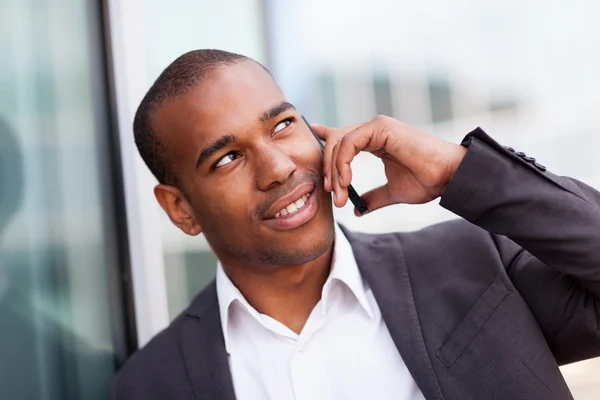 Empresário africano bem sucedido a telefonar enquanto sorri — Fotografia de Stock