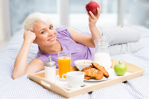 Junge blonde Frau frühstückt im Schlafzimmer — Stockfoto
