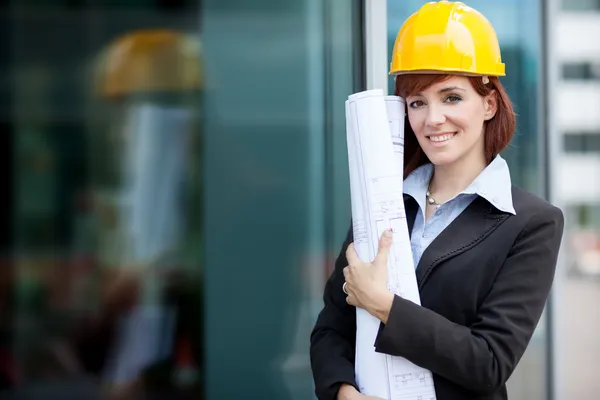 Construtora feminina sorridente em seguida um edifício de vidro — Fotografia de Stock