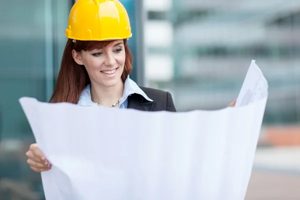 Glimlachend vrouwelijke constructor met blauwdrukken — Stockfoto