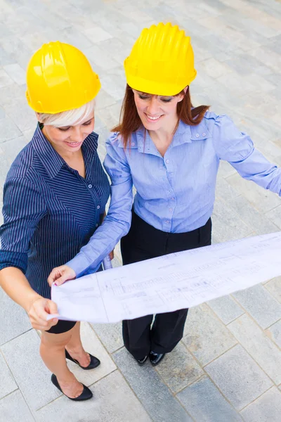 Female constructors holding the project in the hands while smili — Stock Photo, Image