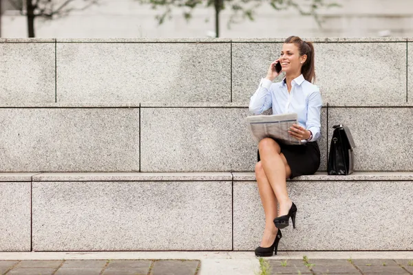 Brunette Femme d'affaires assise dans un escalier avec un journal — Photo