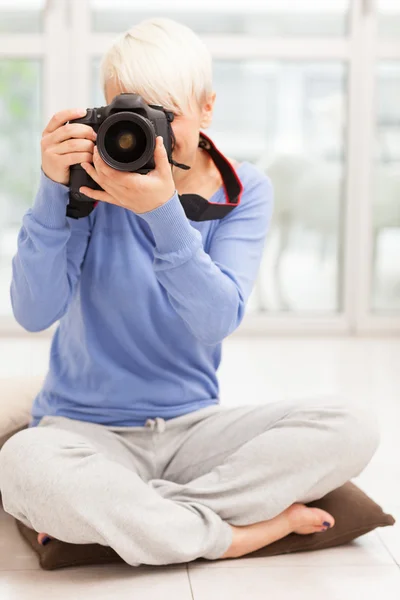 Vrouwelijke fotograaf met dslr thuis zittend op de vloer — Stockfoto