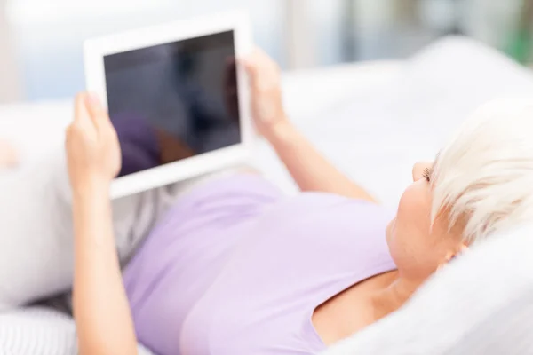 Leende kvinna i sängen med TabletPC — Stockfoto